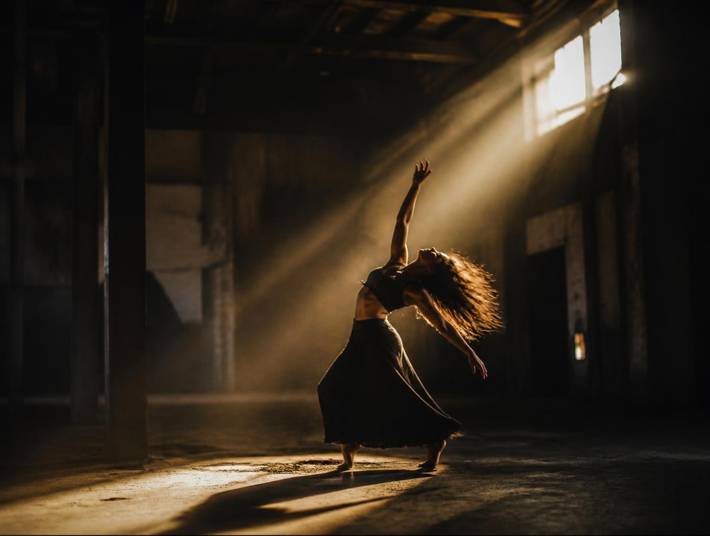 A dancer mid-movement in a shaft of golden light